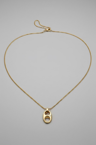 A gold chain necklace featuring a small oval pendant with a central cutout and a tiny clear stone