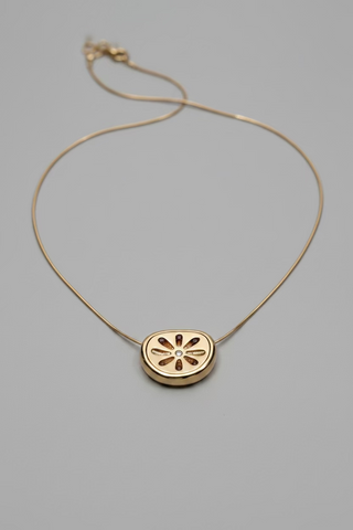 A delicate gold chain necklace with a small oval pendant featuring a cutout flower design