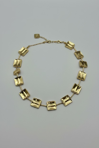 A gold-toned chain necklace featuring a series of polished, reflective square link charms.