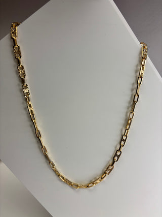 A gold chain necklace with alternating smooth and textured links, displayed on a white jewelry bust.