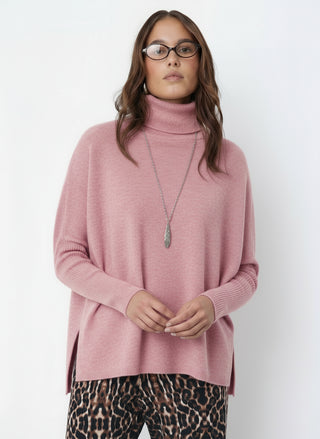 Woman wearing a pink turtleneck sweater and leopard print pants on a white background