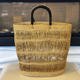 Woven basket with black handle on a white surface