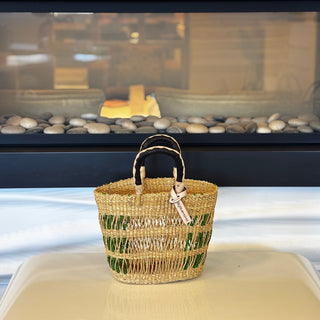 Woven basket with decorative elements on a surface in front of a fireplace.