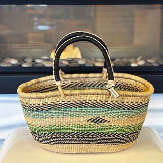 Woven basket with striped handle on a white surface
