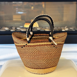 Woven basket with black handles on a white surface