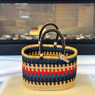 Woven basket with black handles on a white surface
