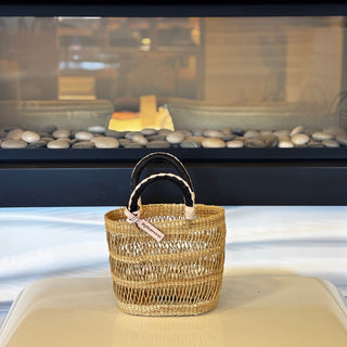 Woven basket with handles on a white surface in front of a fireplace.