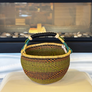 Woven basket with a handle on a white surface, blurred background