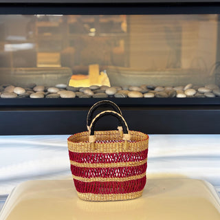 Woven basket with red and beige stripes on a white surface with a blurred background