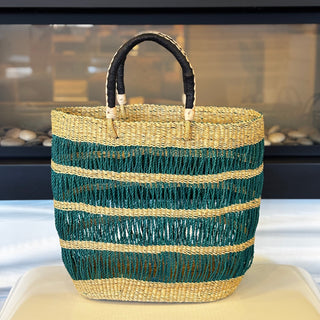 Woven basket with green and beige stripes on a white surface